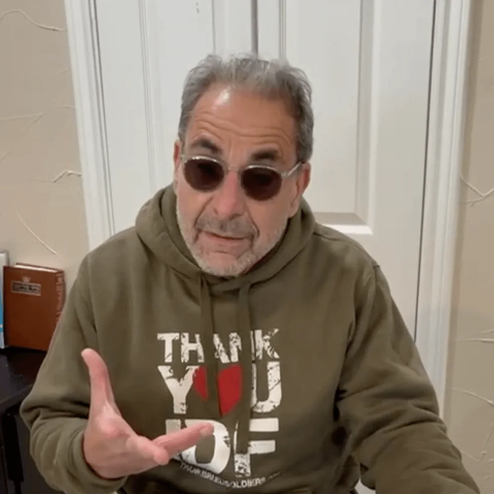 Ivan Sacks speaking to camera at home, wearing a Thank You IDF sweatshirt