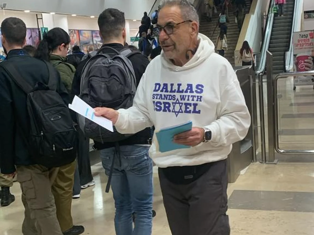 Ivan Sacks in a Dallas Stands With Israel sweatshirt holding travel documents in an airport terminal