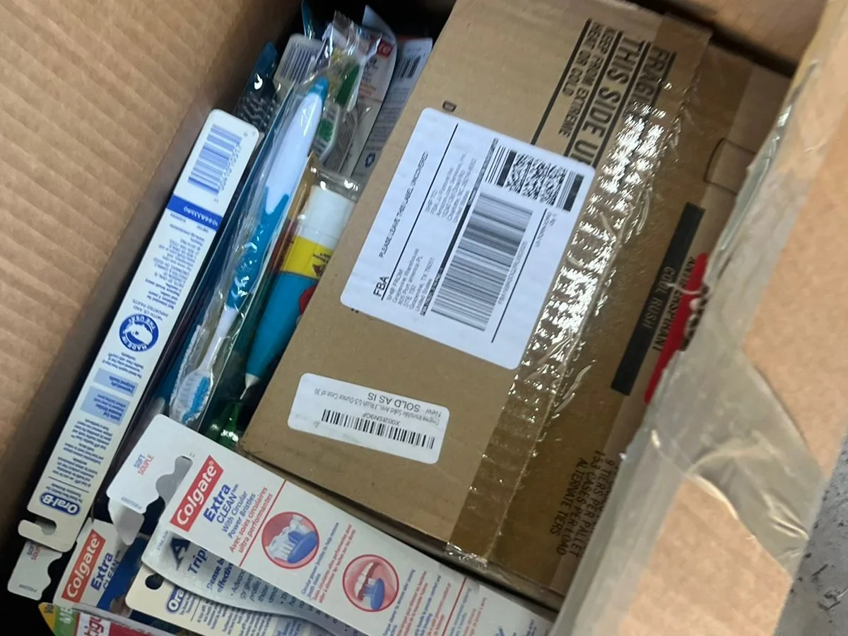 An opened box of donated supplies — toothbrushes, pens and toiletries — packed around a shipping carton