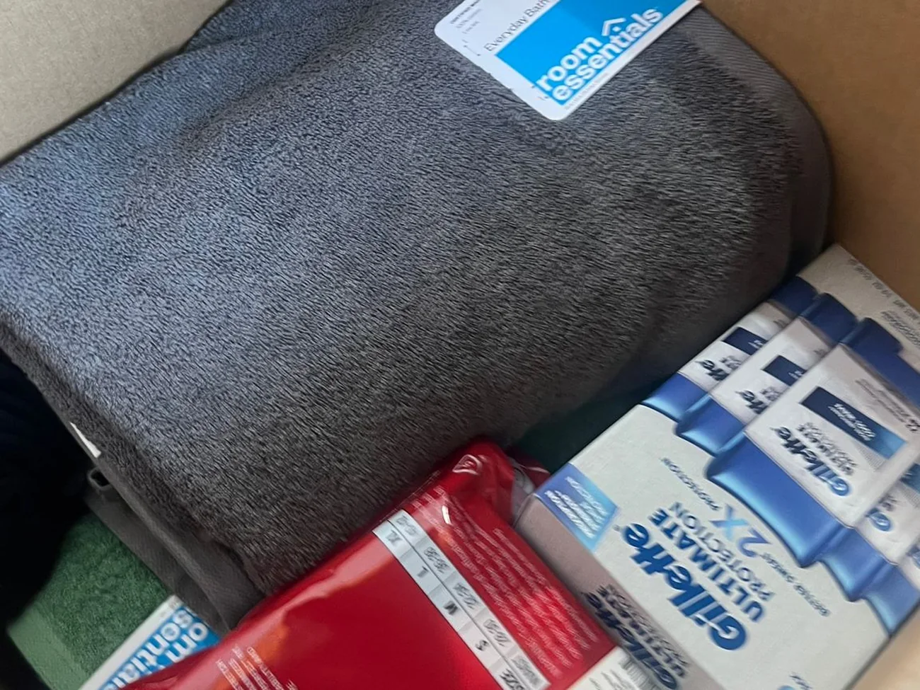An open box of donated supplies containing a fleece blanket, razors and toiletries
