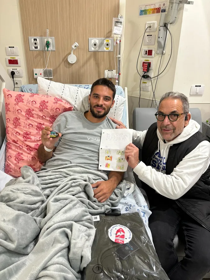 Ivan Sacks at the bedside of an injured soldier, who is holding a child’s illustrated letter