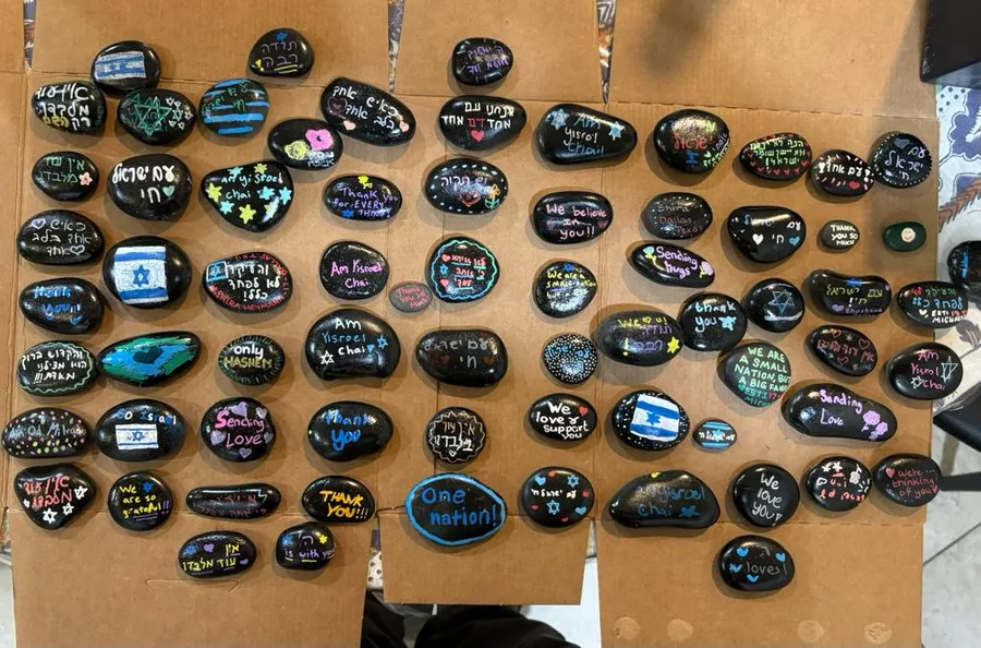 A board covered with dozens of hand-painted stones carrying messages and Israeli flags
