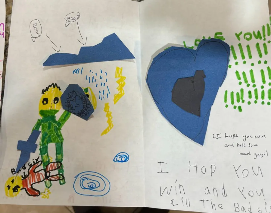 A child’s letter covered in crayon drawings, hearts and a large blue heart cut-out