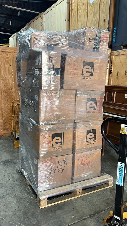 A shrink-wrapped pallet of donated supply boxes on a pallet jack, marked with the Element Moving logo